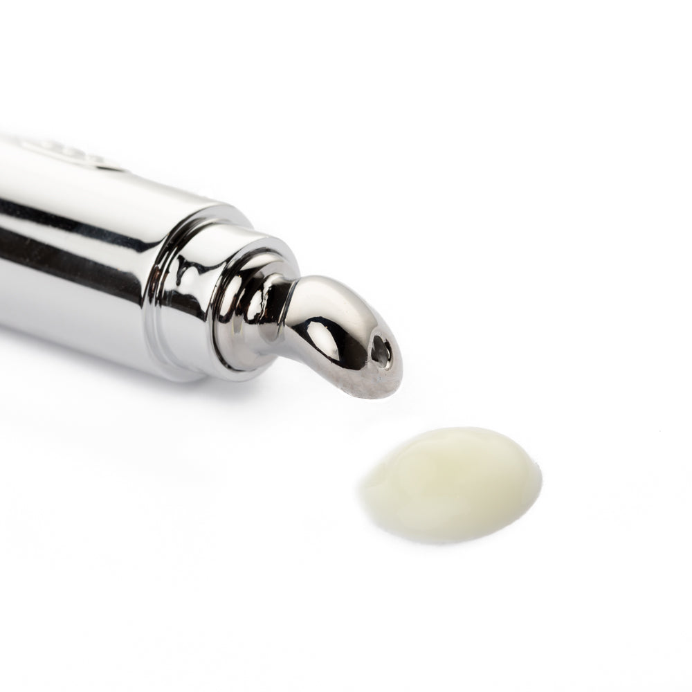 Silver cosmetic applicator with a drop of cream on a white background