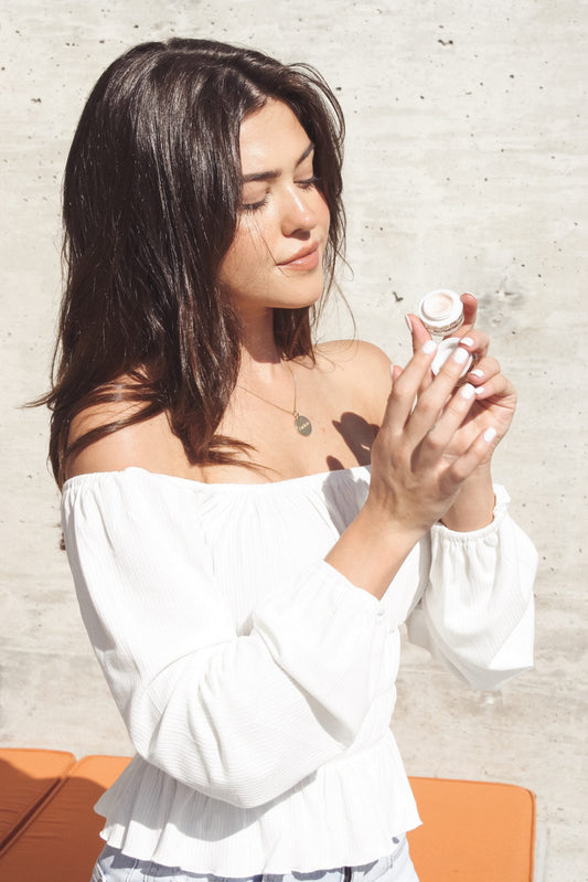 Woman holding a small bottle against a light-colored wall