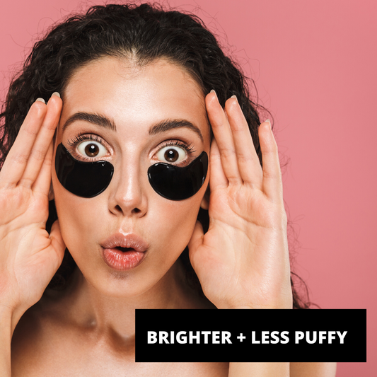 Woman applying eye patches with text 'Brighter + Less Puffy' on a pink background