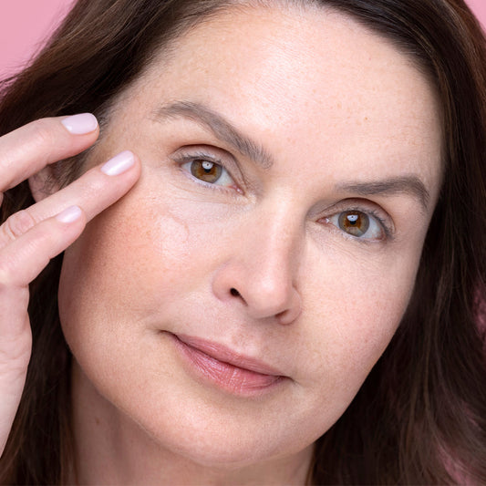 Woman touching her face with a pink background