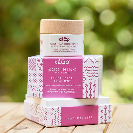 Kéap soothing body balm packaging on a wooden surface with a blurred green background